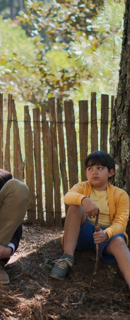 Man and a child in front of a fence, scene from a film. Photo/image: ‘The Book of Love’ courtesy of XYZ Films